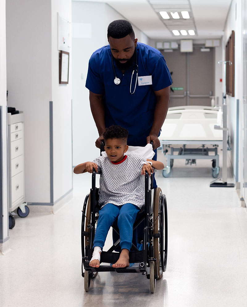 ABW Medical privia health centers male nurse assisting young patient in wheelchair
